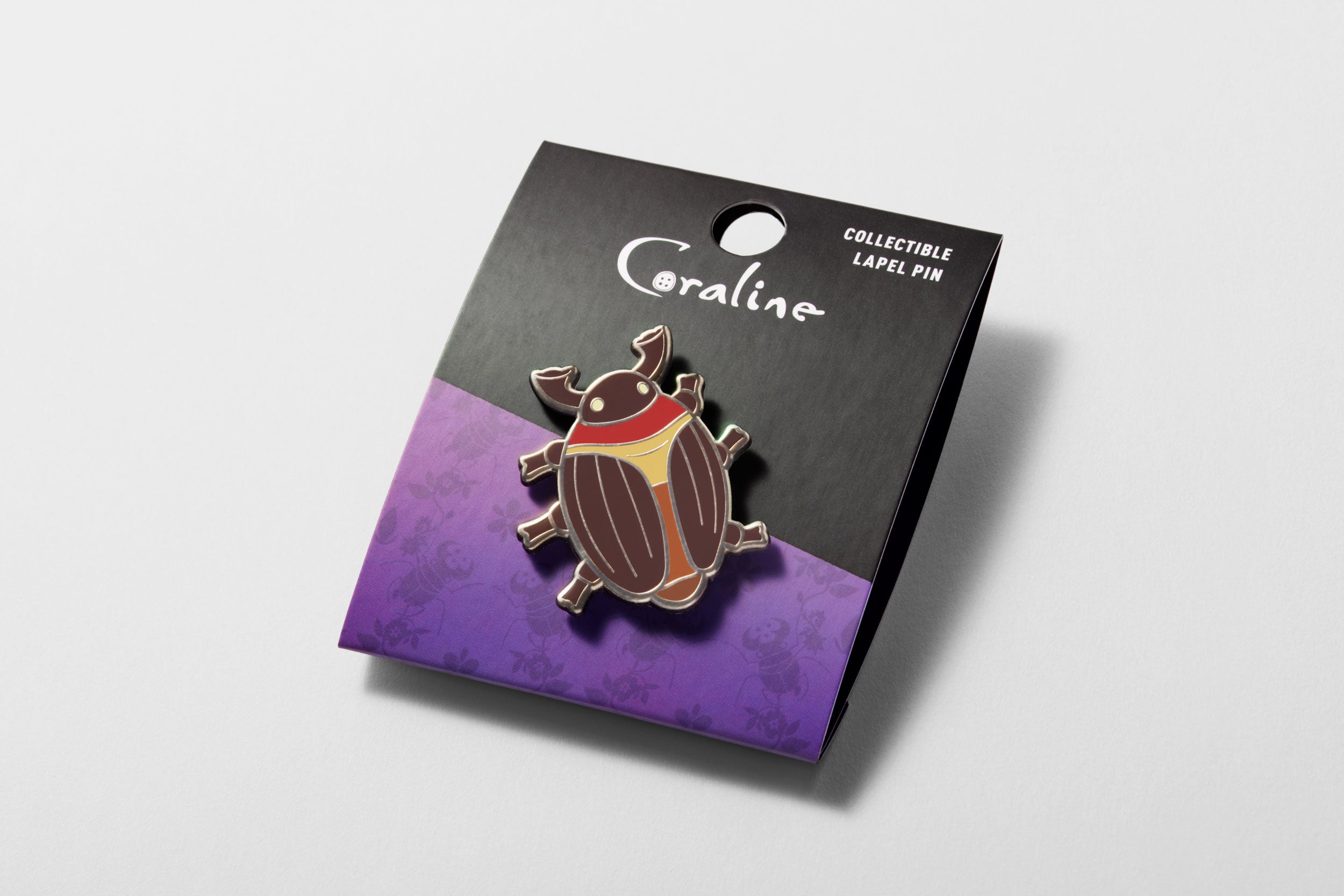 Cocoa Beetle enamel with black and purple backer card, angled to show gold detailing shining in the light Image